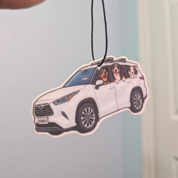 A finished white SUV air freshener with three dogs looking out of its side windows.